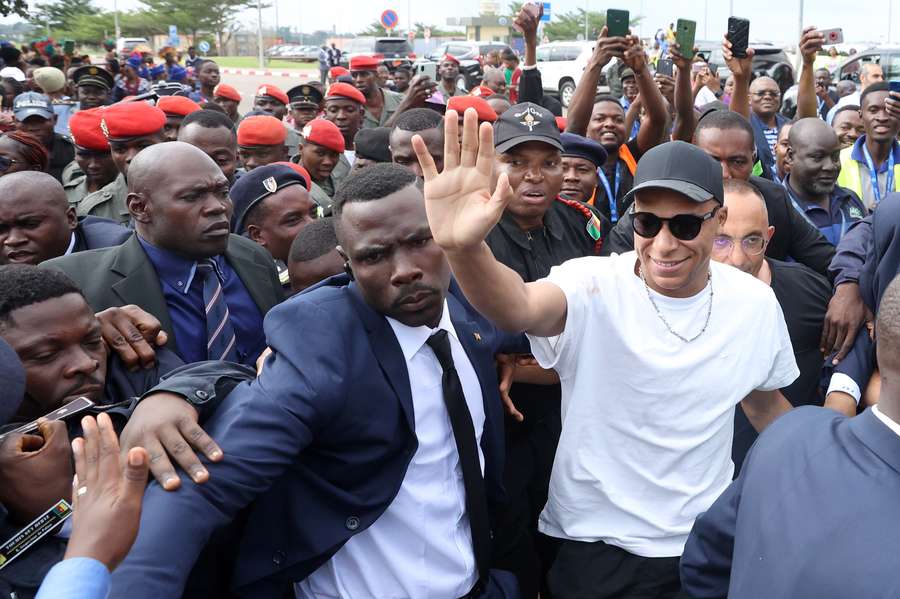 Paris Saint-Germain and France national football team star striker Kylian Mbappe (C-R) greets crowds gathered outside at the Yaounde Airport