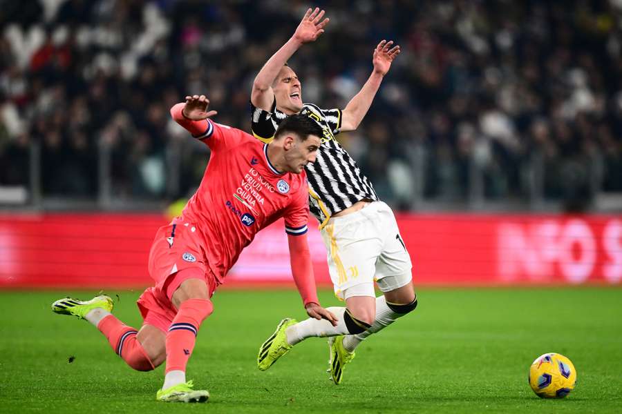 Udinese’s Lorenzo Lucca (L) fights for the ball with Juventus forward Arkadiusz Milik