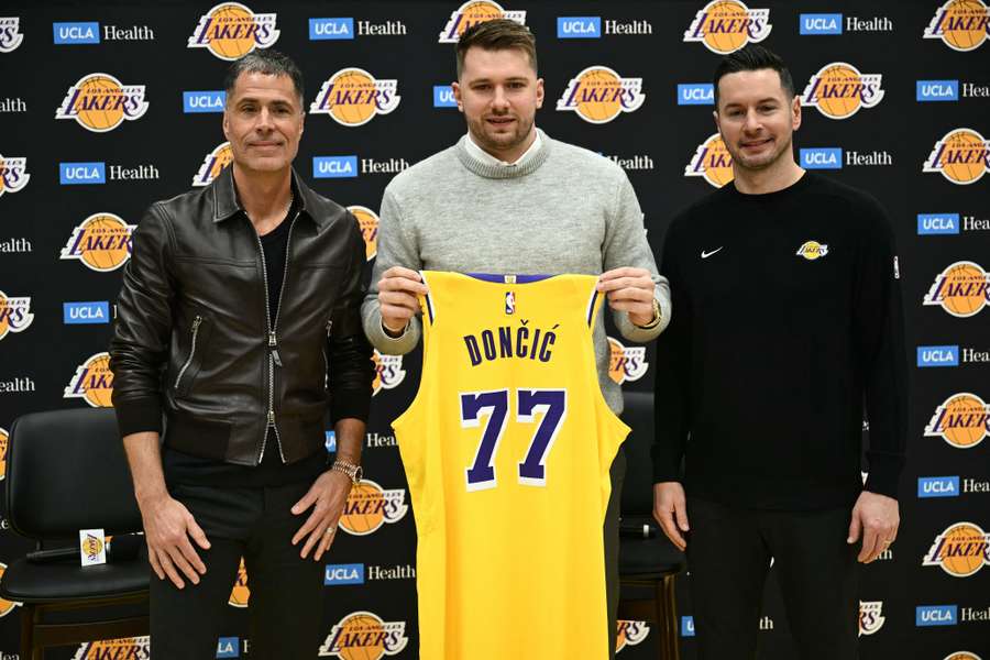 Luka Doncic, centre, holds up a jersey as he stands alongside Lakers head coach JJ Redick, right, and general manager Rob Pelinka