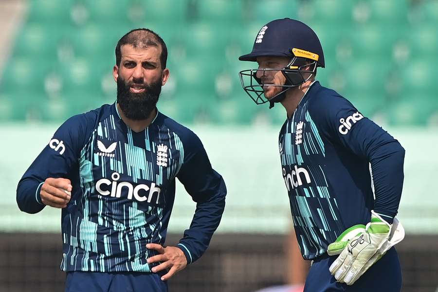 England captain Jos Buttler (R) speaks with teammate Moeen Ali 