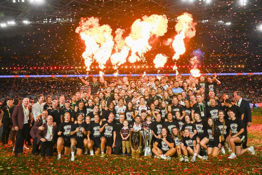 The title-winning Brisbane Broncos NRL and NRLW squads pose for a group photo with their trophies. 
