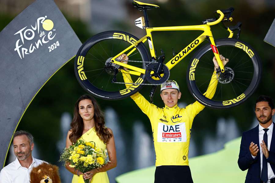 Tadej Pogacar lifts his bike after winning the Tour de France