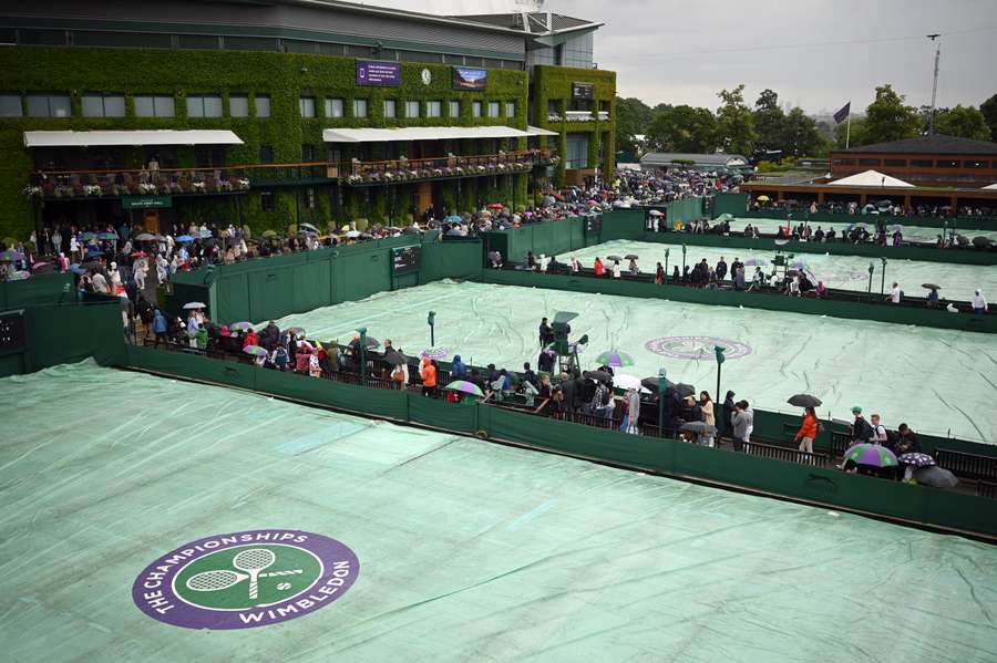 Protective covers are unfolded over the courts as rain starts to fall