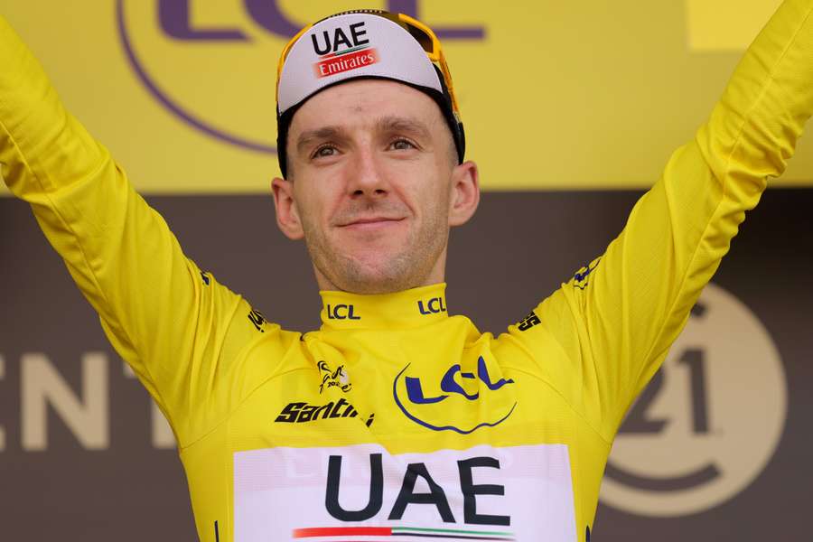 UAE Team Emirates' Adam Yates celebrates on the podium with the overall leader's yellow jersey