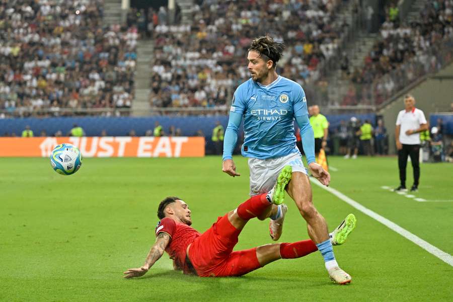 O médio inglês do Manchester City, Jack Grealish, e o avançado argentino do Sevilha, Lucas Ocampos, lutam pela bola