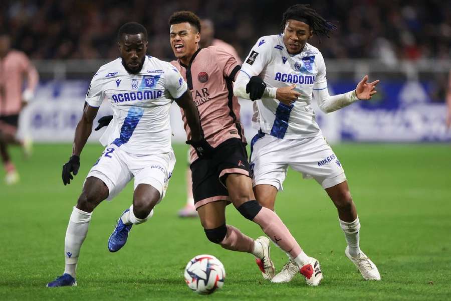 Auxerre's Elisha Owusu (left), Paris Saint-Germain's Desire Doue (centre) and Auxerre's Gabriel Osho (right) fight for the ball
