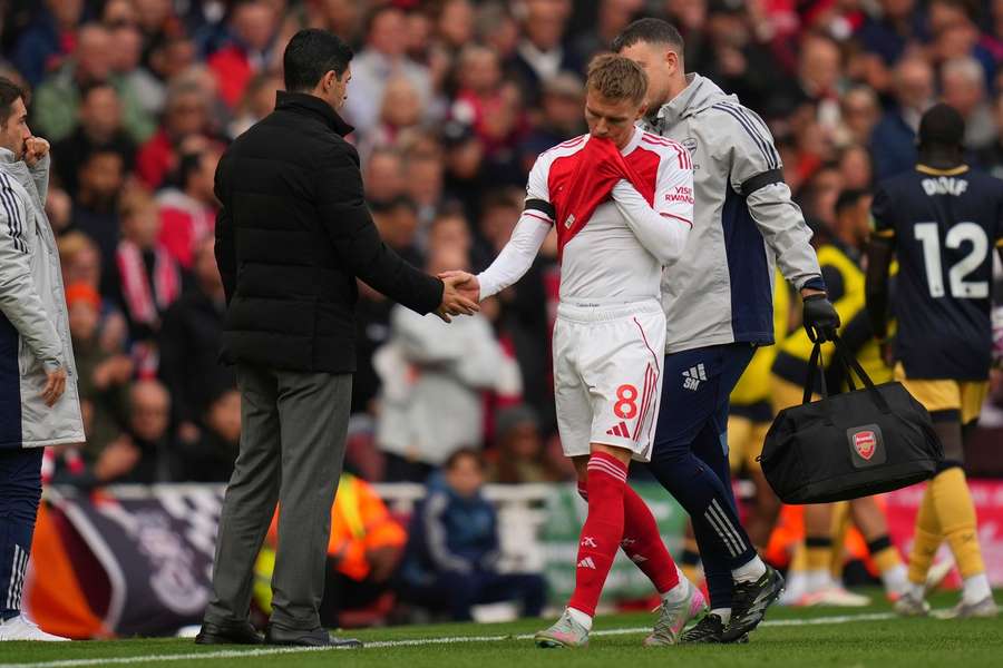 Arsenal's Martin Odegaard, centre, shakes hands with Arsenal's manager Mikel Arteta during the substitution