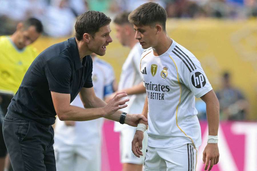 Real Madrid's Spanish coach Xabi Alonso (L) speaks to Real Madrid's Turkish midfielder #15 Arda Guler (R)