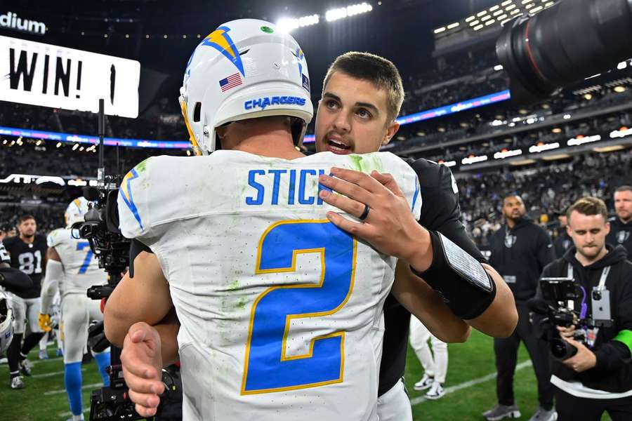 Quarterback Aidan O'Connell (Raiders) wordt gefeliciteerd door zijn collega-QB Easton Stick (Chargers)