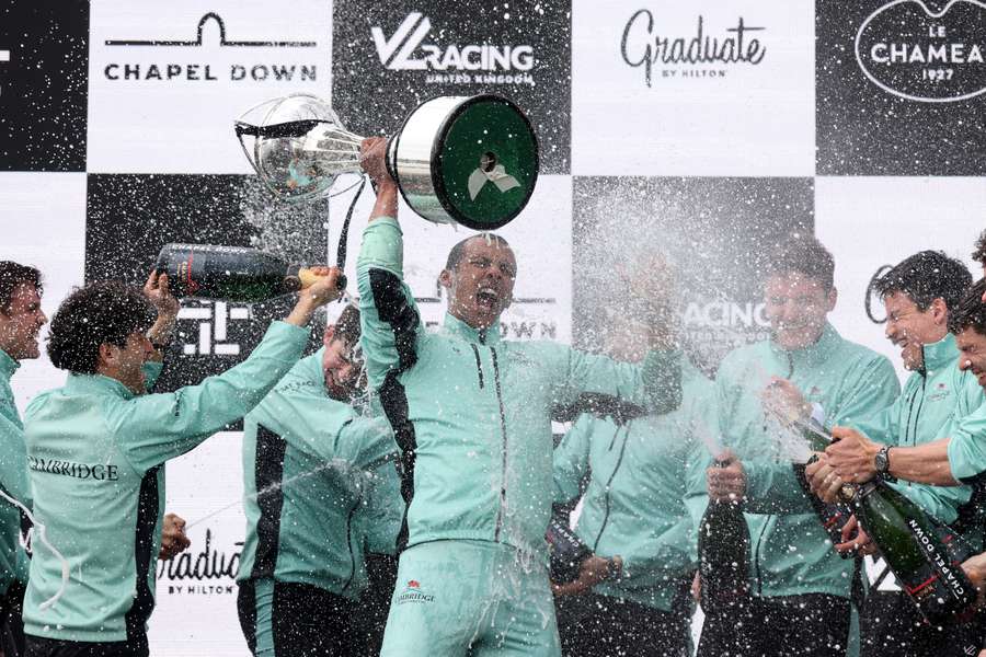 Noam Mouelle of Cambridge University lifts the trophy and celebrates with his crew mates