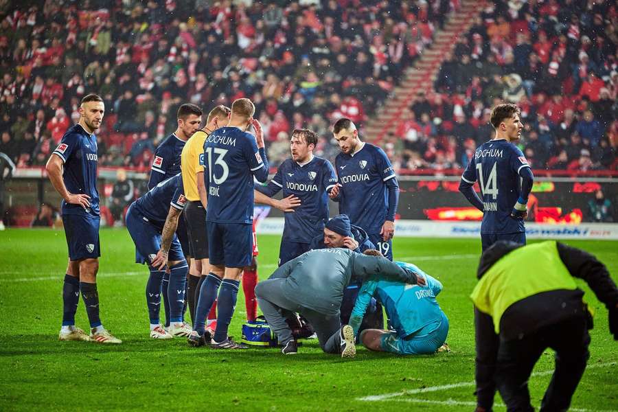 Jucătorii de la Bochum se adună în jurul portarului Patrick Drewes, care primește îngrijiri medicale după ce a fost lovit în cap cu o brichetă