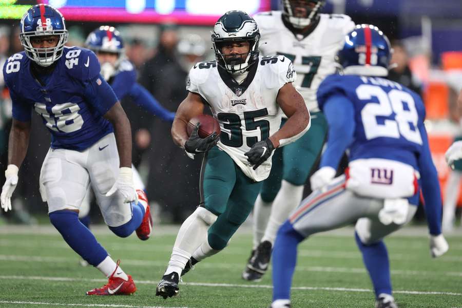 Boston Scott of the Philadelphia Eagles runs the ball against Tae Crowder and Cor'Dale Flott of the New York Giants