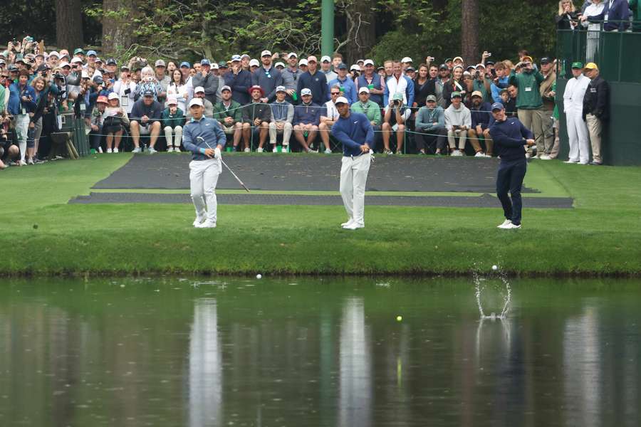 Tom Kim of South Korea, Tiger Woods of the United States and Rory McIlroy of Northern Ireland skip their ball across the pond on the 16th hole during a practice round