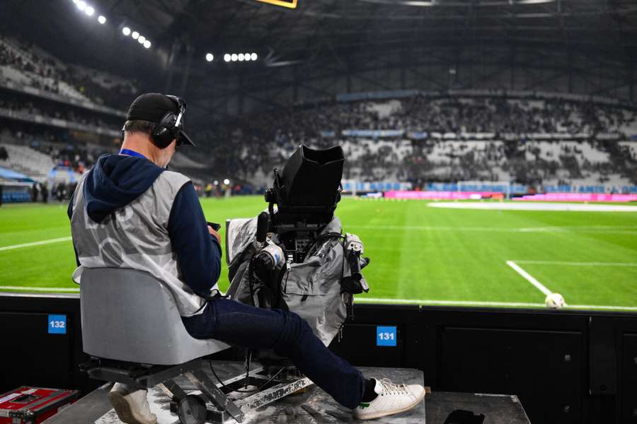 A cameraman sits as spectators leave the Stade Velodrome after the French Ligue 1 football match between Marseille and Lyon was postponed