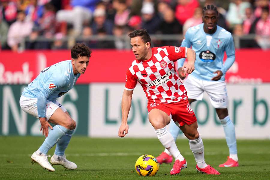 Arthur Melo of Girona runs with the ball under pressure from Pablo Duran of Celta Vigo