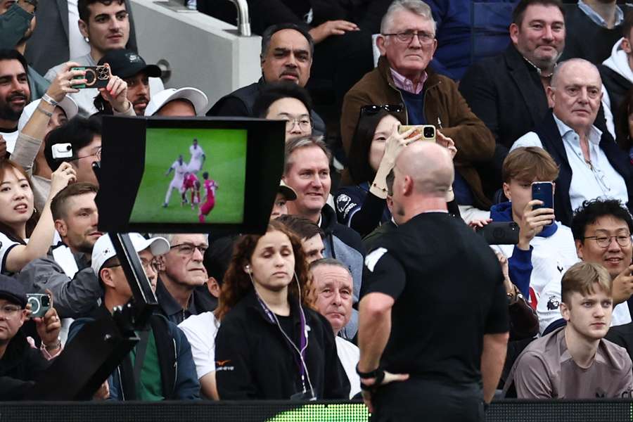 Referee Simon Hooper watches a VAR during the English Premier League football match between Tottenham Hotspur and Liverpool