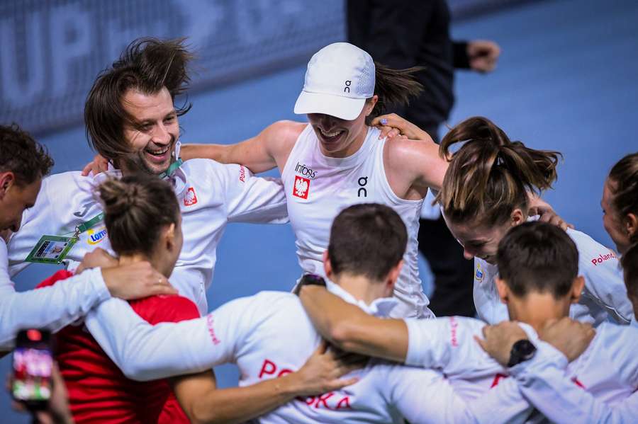 Poland's Iga Swiatek (top center) celebrates with teammates and coaches after winning her match against Spain's Paula Badosa