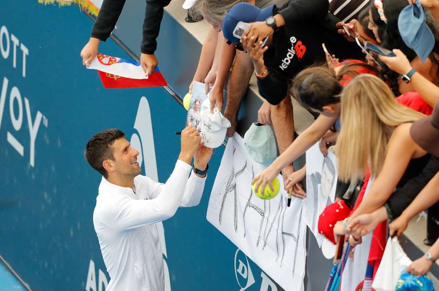 Een blije Djokovic deelt handtekeningen uit na zijn overwinning op Lestienne