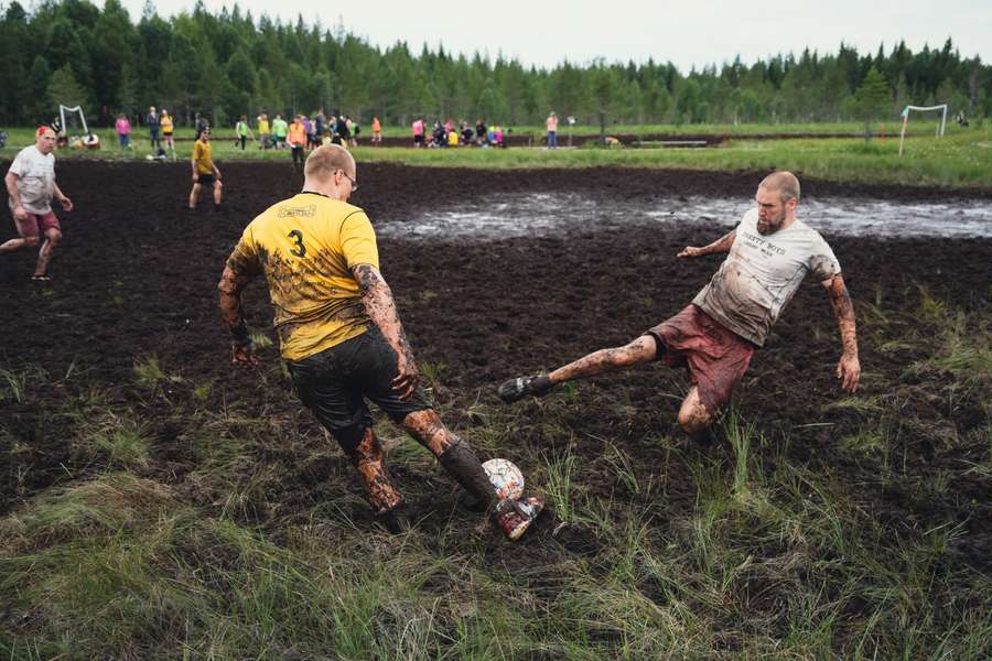 Players vie for the ball during a match of swamp soccer on July 15, 2023 at the Swamp Soccer World Cup in the swamps of Vuorisuo in Hyrynsalmi municipality