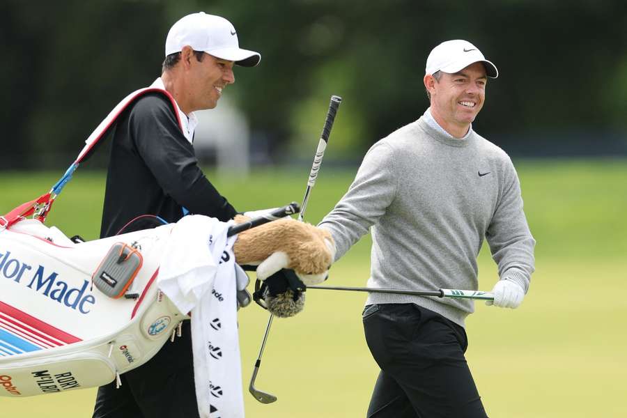 Rory McIlroy troca de taco com o seu caddie Harry Diamond enquanto percorrem o 13.º buraco durante uma ronda de treinos antes do PGA Championship