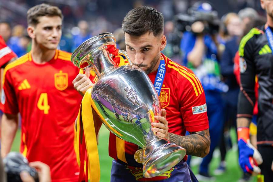 Baena pose avec le trophée de l'Euro remporté par l'Espagne en Allemagne, avec Gavi en arrière-plan.