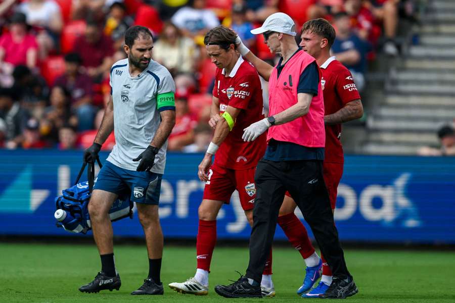 Craig Goodwin leaves the field with the Adelaide United medical team last weekend.