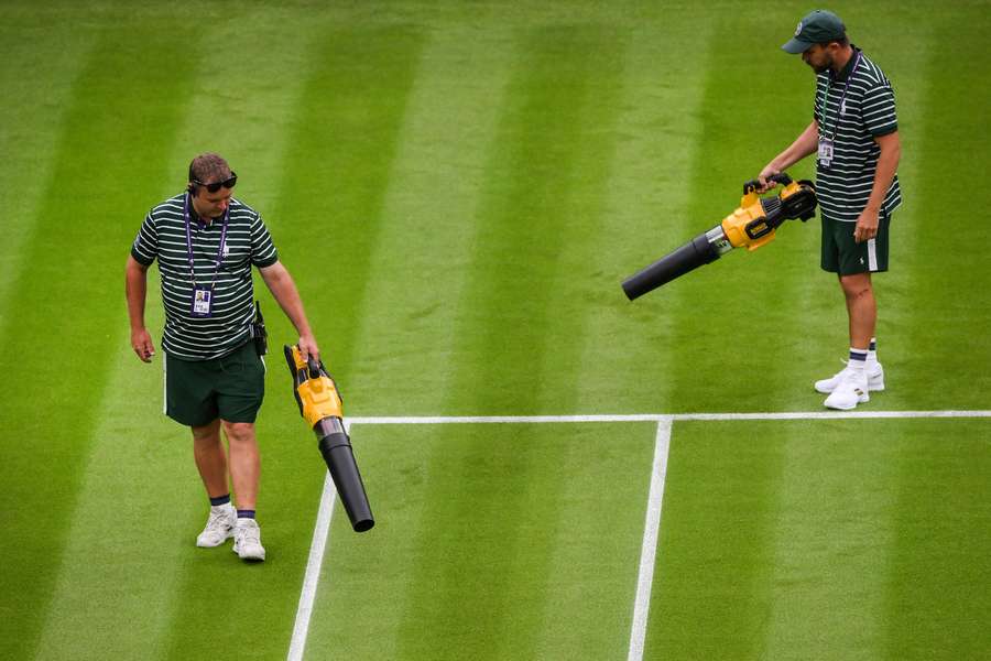 Il personale di Wimbledon ha asciugato la superficie del campo centrale con macchine manuali.