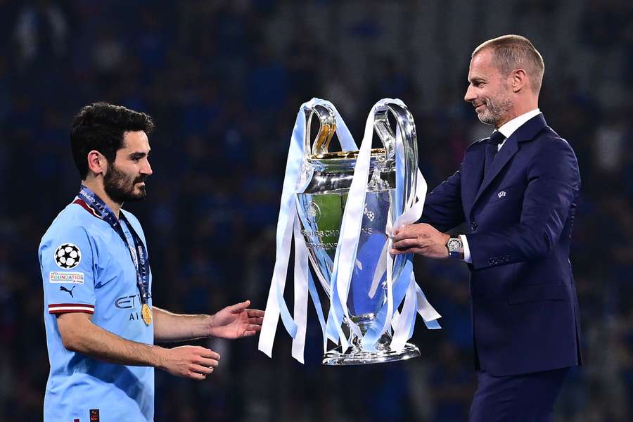 UEFA president Aleksander Ceferin (R) presents the Champions League trophy to Manchester City midfielder Ilkay Gundogan