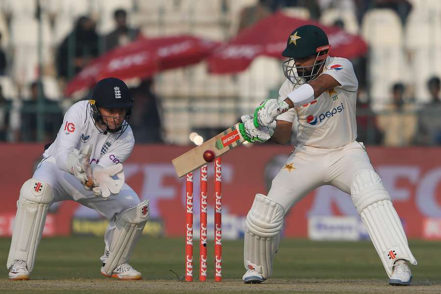 Pakistan captain Babar Azam (R) plays a shot as England wicketkeeper Ollie Pope watches on