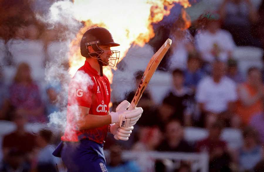 Angličan Will Jacks odchází před zápasem s Novým Zélandem, když za ním stříká oheň.