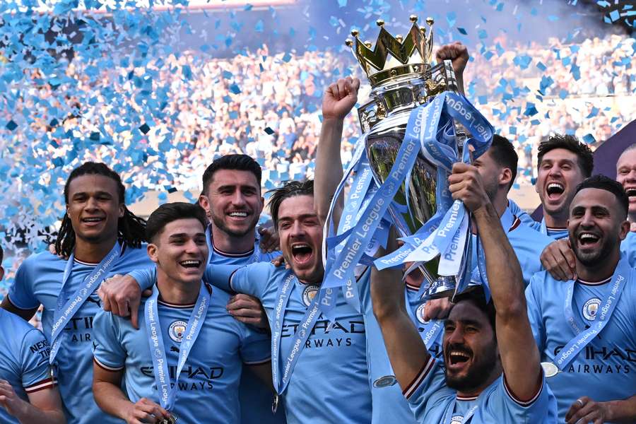 O meio-campista alemão do Manchester City, Ilkay Gundogan, levanta o troféu enquanto os jogadores do Manchester City comemoram