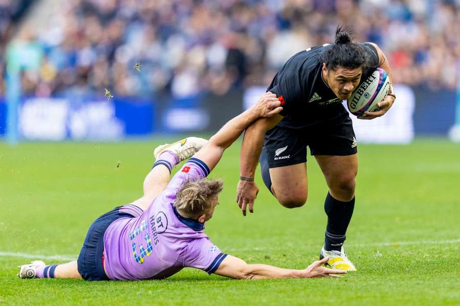 Caleb Clarke of New Zealand evades a challenge from Chris Harris of Scotland