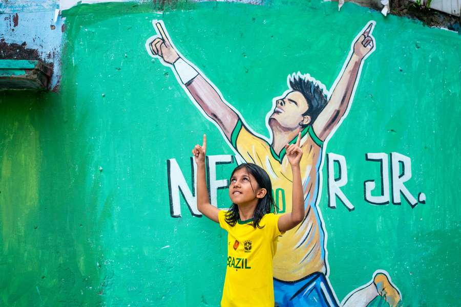 Pequena torcedora defronte pintura de Neymar em Chittagong, Bangladesh Pequena torcedora defronte pintura de Neymar em Chittagong, Bangladesh