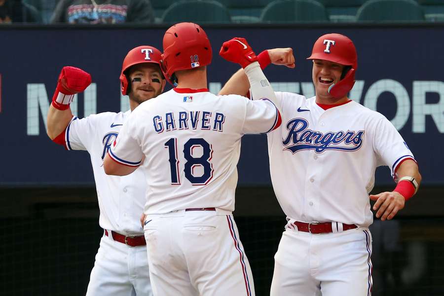 Robbie Grossman en Josh Jung feliciteren Mitch Garver na diens three-run home run in de zevende inning