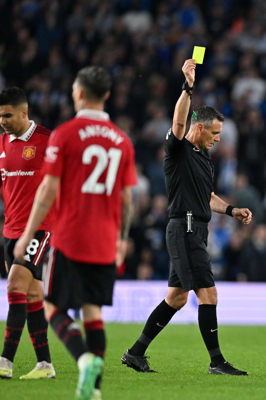 Andre Marriner shows a yellow card to Casemiro