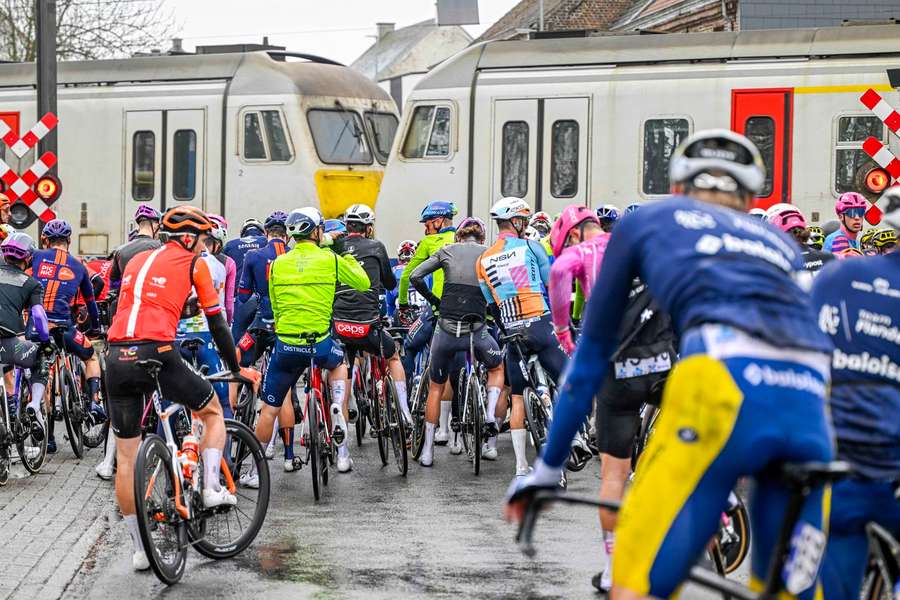 Riders wait in front of a railway crossing during the Tour of Flanders Riders wait in front of a railway crossing during the Tour of Flanders