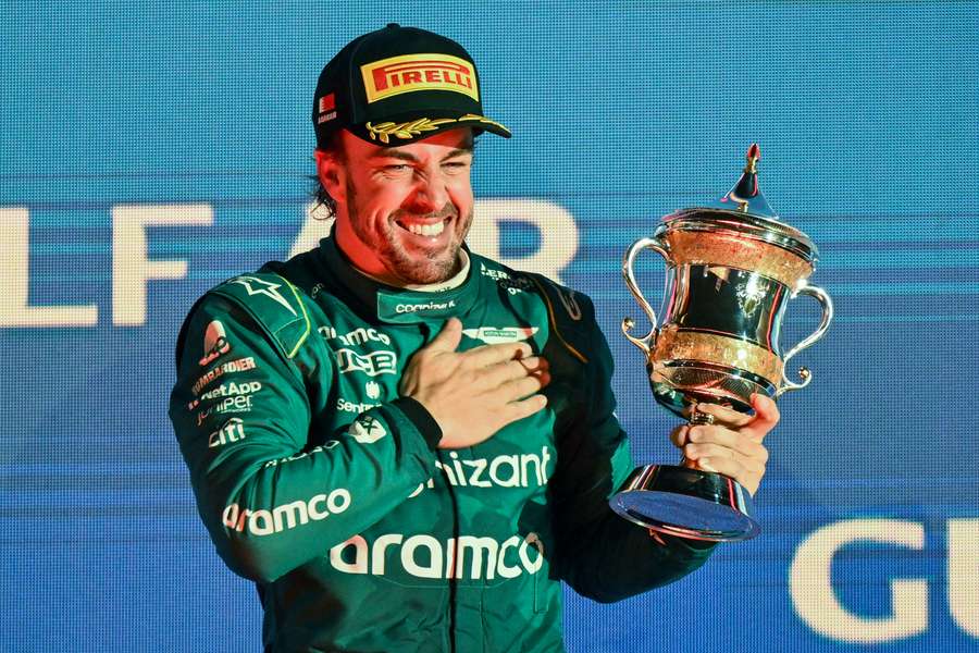 Aston Martin's Spanish driver Fernando Alonso celebrates on the podium with the third-place trophy 