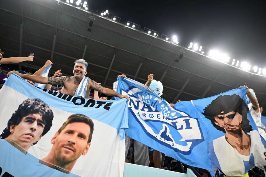 Argentina supporters wave flags depicting portraits of football legend Diego Maradona and Lionel Messi