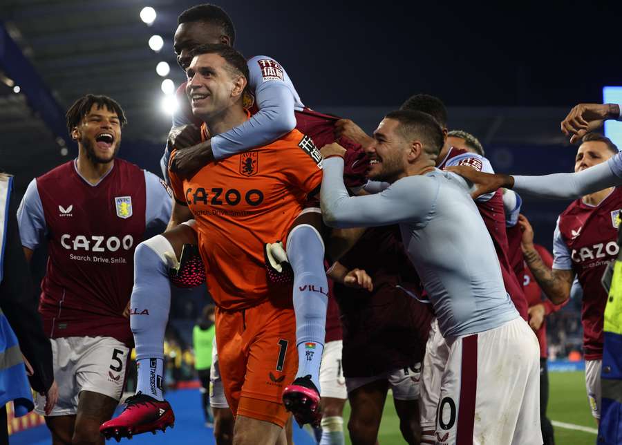 Aston Villa's Burkinese midfielder Bertrand Traore jumps on the back of Aston Villa's Argentinian goalkeeper Emiliano Martinez after scoring