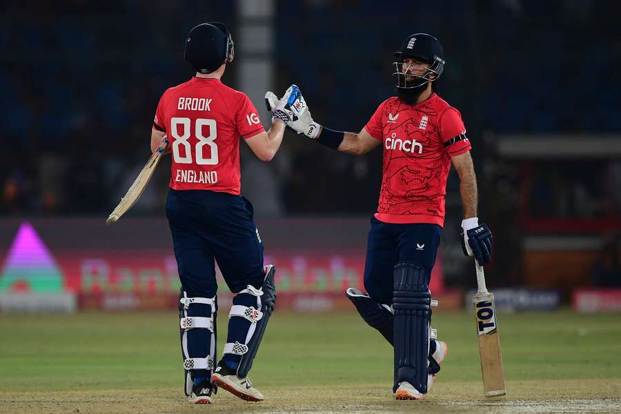 England's captain Moeen Ali (R) celebrates with teammate Harry Brook after beating Pakistan by six wickets.