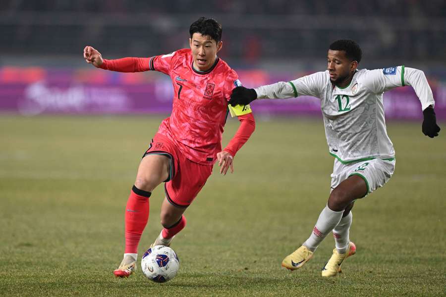 South Korea's Son Heung-min (L) competes for the ball with Oman's Abdullah Al-Harthi