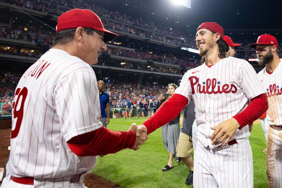 Philadelphia Phillies manager Rob Thomson (L) shakes hands with starting pitcher Michael Lorenzen