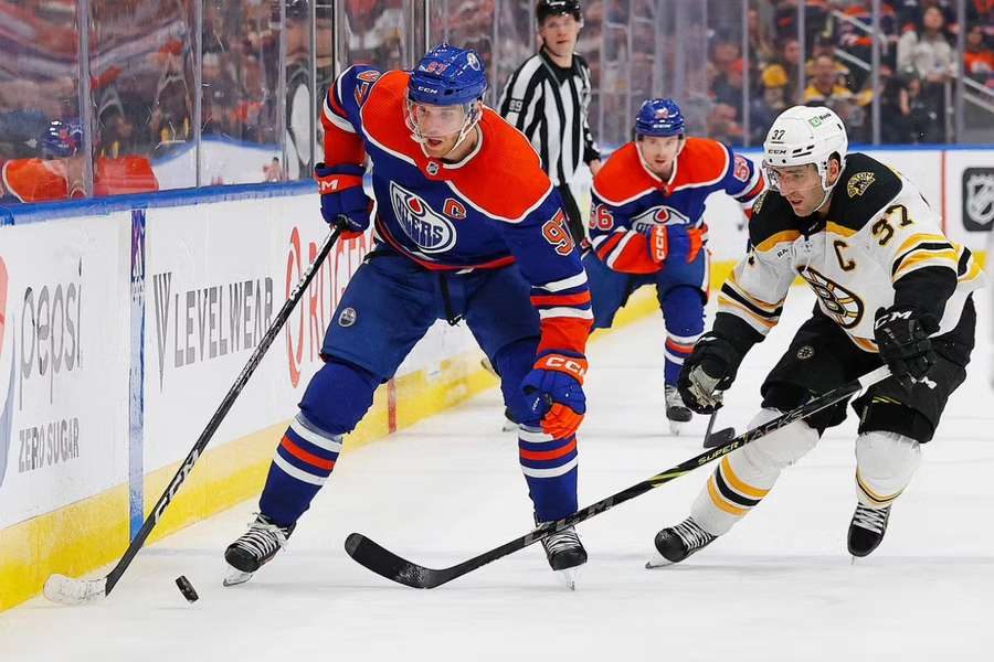 McDavid carries the puck around Boston Bruins forward Bergeron