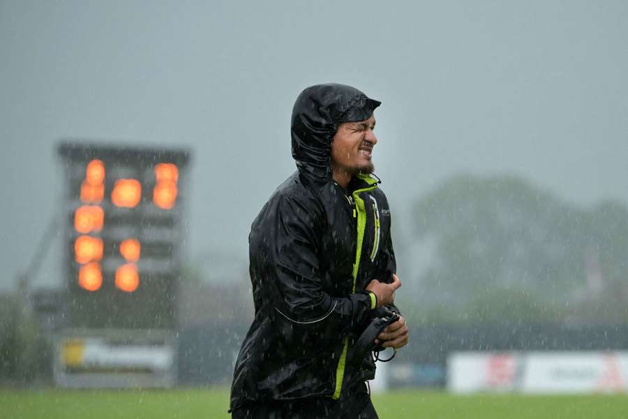 An official runs for cover as heavy rain peppers the Bready Cricket Club in Derry. 