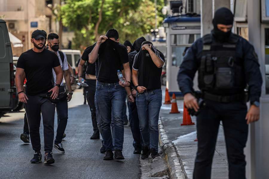 Football fans, most of them from Croatia, cover their faces while leaving the Athens Police Headquarters in Athens