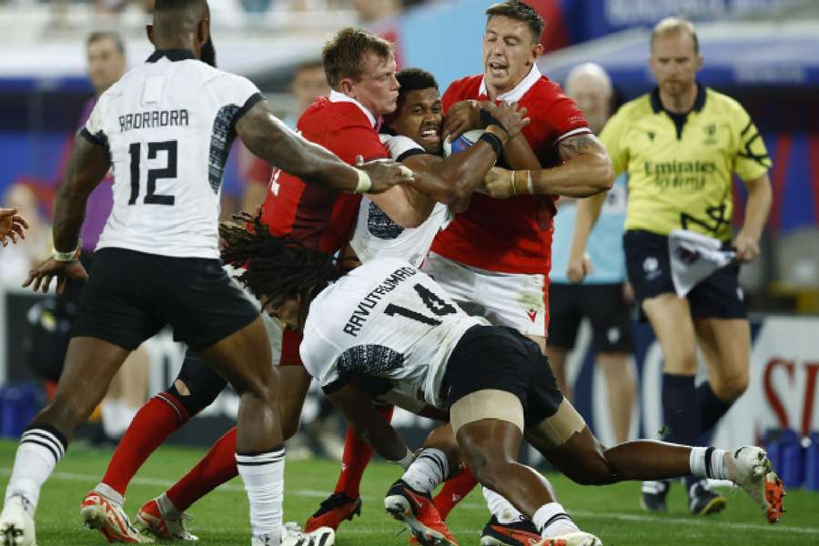 Fiji's Ilaisa Droasese in action with Wales' Nick Tompkins and Josh Adams