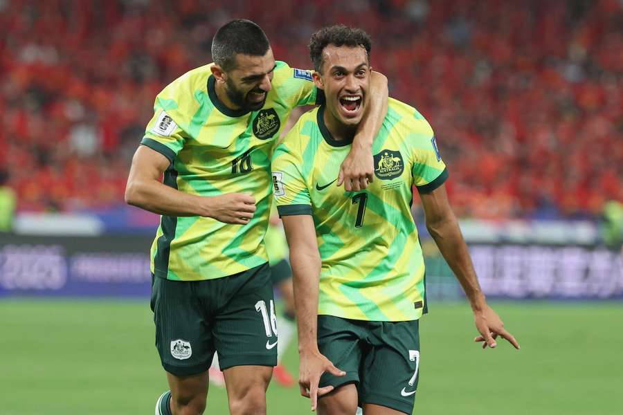 Nishan Velupillay celebrates his FIFA World Cup qualification goal against China with teammate Aziz Behich.