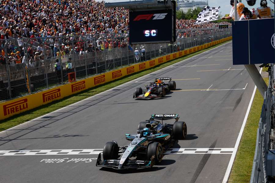 George Russell projíždí cílem před Maxem Verstappenem.