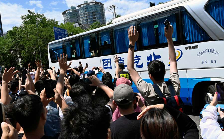 Aficionados chinos saludan y hacen fotos al paso del bus de Argentina.