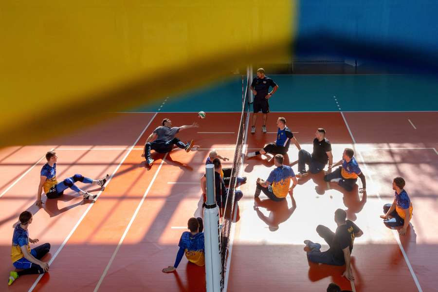 Yevhenii Korinets e outros membros da equipa paraolímpica de voleibol sentado treinam num ginásio em Reshetylivka